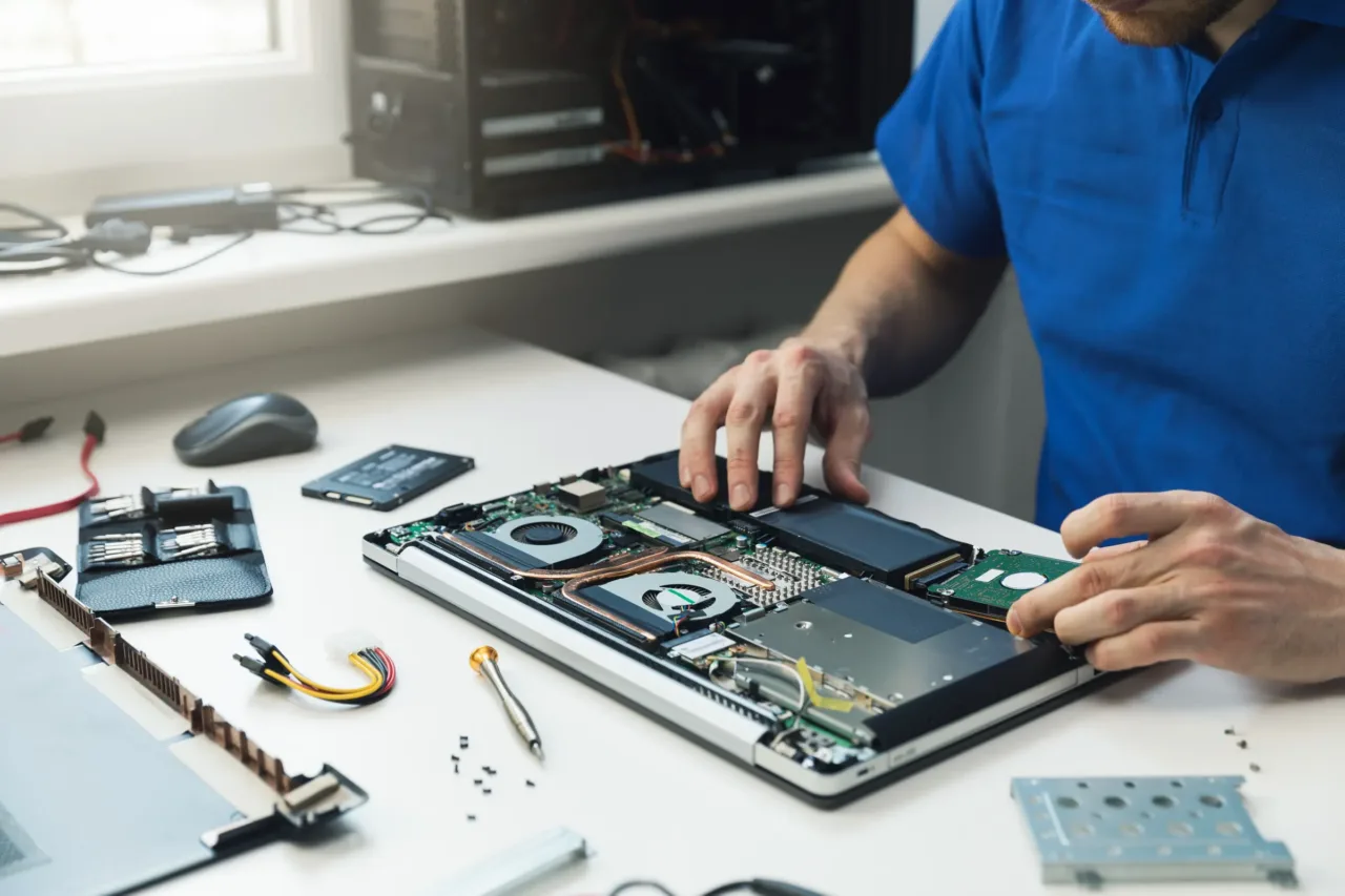 Geöffneter Laptop auf der Werkbank – der Techniker baut die Festplatte aus