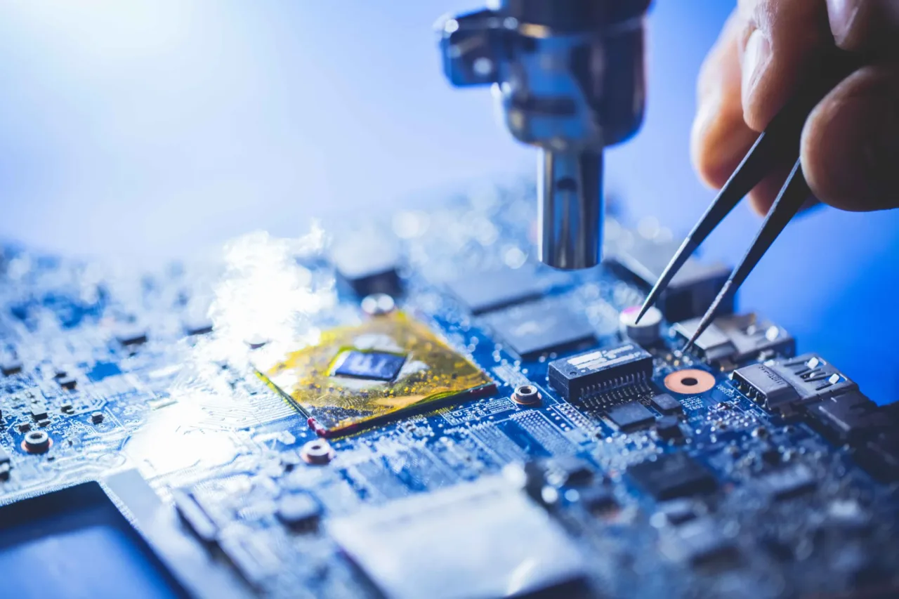 Lötkolben und Pinzette bei der Reparatur einer blauen Platine